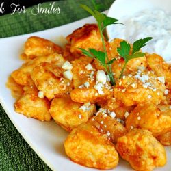 buffalo boneless wings on a white plate with a small sauce and ranch on upper right corner of plate all on a green placemat