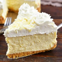 closeup slice of vanilla bean cheesecake with whipped cream.