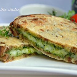 pesto grilled cheese cut in 2 on white plate
