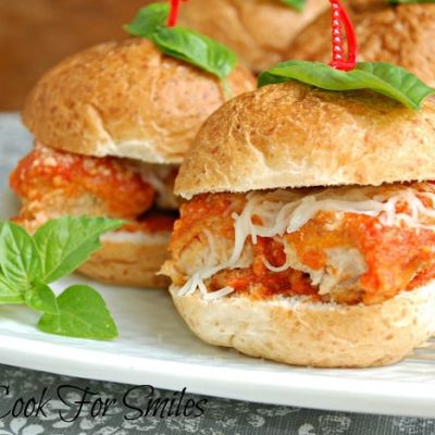 4 chicken parmesan sliders on a white rectangular plate on a white and grey cloth on woodem table