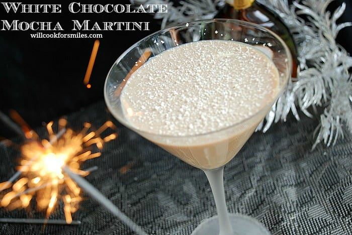 White Chocolate Mocha Martini in a martini glass with white chocolate shavings on top with a sparkler to the left 