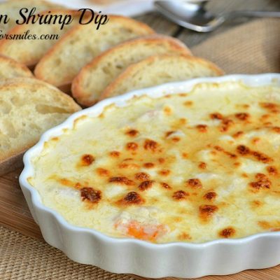 bowl of parmesan shrimp dp with bread for dipping on wood presenter.