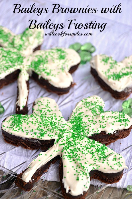 Brownies cut in a clover shape with white frosting and green sprinkles on top 