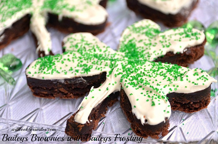 Brownies cut in a clover shape with white frosting and green sprinkles on top 