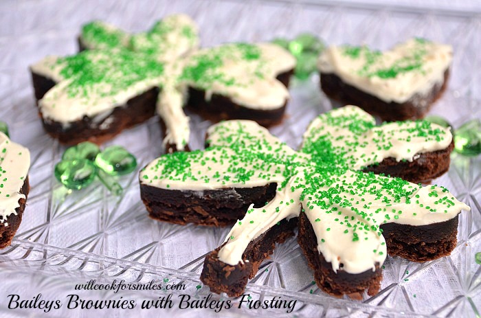 Brownies cut in a clover shape with white frosting and green sprinkles on top 