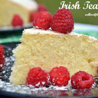 close-up view of irish tea cake and raspberries slice on plate with whole cake in background