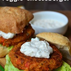 2 chili lime burgers on buns with creamy topping on wood cutting board and additional cream sauce to the right