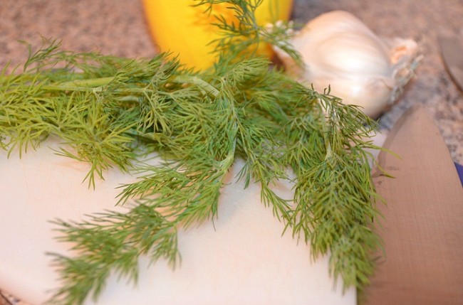 dill, lemon, and garlic on a cutting board 