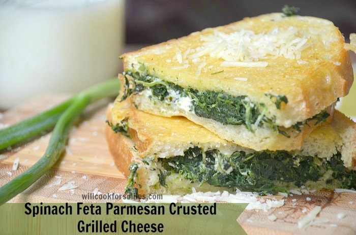 Spinach Feta Parmesan Crusted Grilled Cheese cut in half on a wood cutting board 