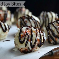 7 almond joy bites on wax paper resting on metal rack. Each bite drizzled with chocolate syrup
