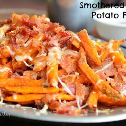 close up shot of smothered sweet potato fries with white sauce cup to right in background