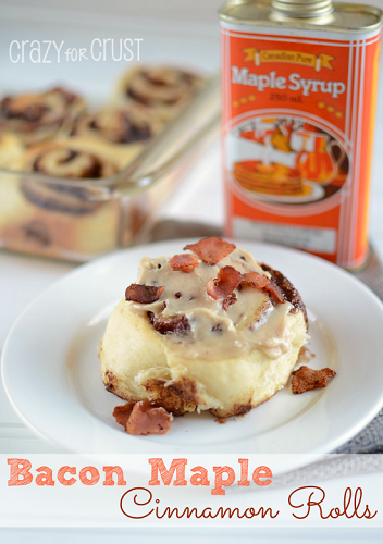 1 bacon maple cinnamom rool on a white round plate in front of a baking pan with more buns and a can of maple syrup in background to the right