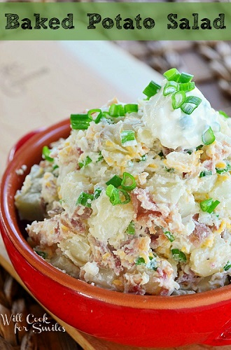 baked potato salad in a red bowl with sour cream and chives on top as garnish 
