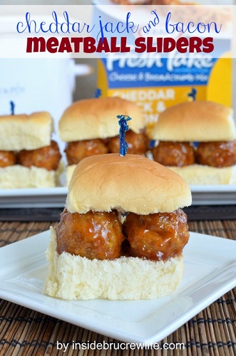 1 meatball sliders on square white plate in front of 3 more sliders in background
