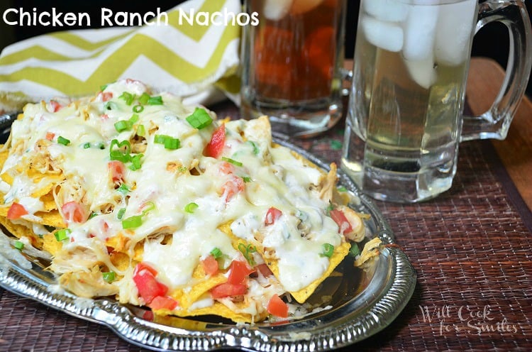 Chicken Ranch nachos on a metal platter with drinks in glass mugs next to it 