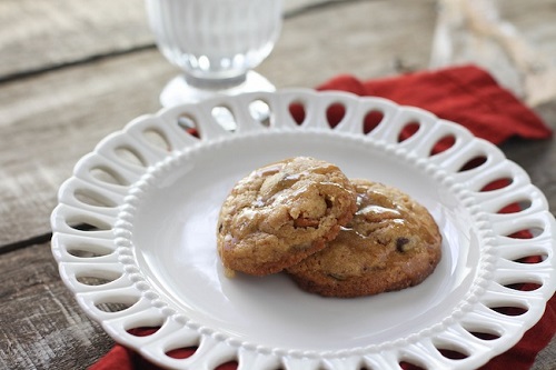 2 cookies on a white round plate with a glass of milk in background to the middle left of frame