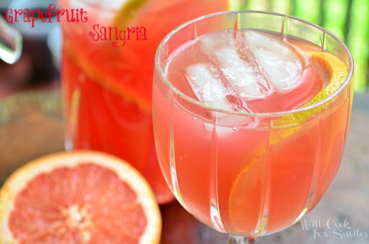 Grapefruit Sangria in a glass with a sliced grapefruit and a pitcher in the background 