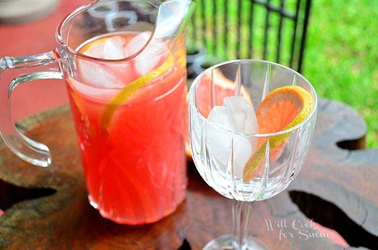 top view grapefruit sangria in a pitcher and a wine glass with ice in it and a grapefruit slice 