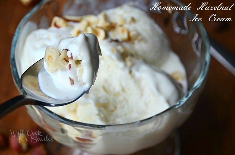 shot from front and slightly above clear glass bowl of hazelnut icecream and spoon to bottom left