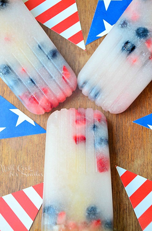 red white and blue ice pops on a wood table with red and white stripped flag and blue flag with stars 