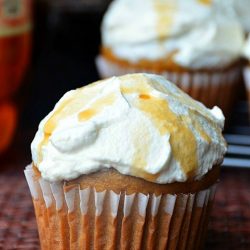 close up shot of root beer cupcakes with additional cupcakes in background and 2 2 liters of soda to the left in back ground