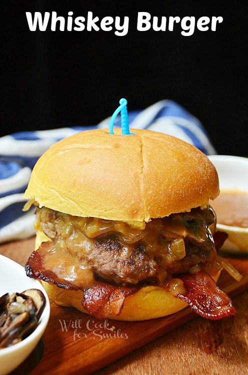 1 whiskey burger on wood cutting board with small white bowl sauce and of mushroom to the left