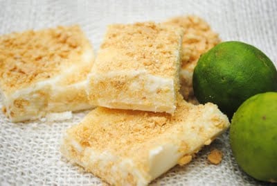 key lime fudge squares on a table cloth with whole limes to the right 
