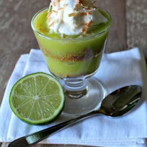 key lime coconut parfaits in a bowl with a spoon to the right and a slice of lime to the right 