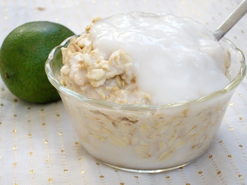 key lime pie oatmeal in a glass bowl with a spoon to the right and a lemon to the left 