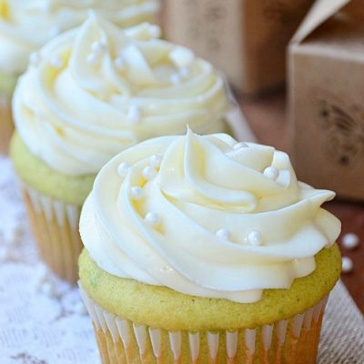 3 avocado cupcakes lined up on decorative cloth on wooden table