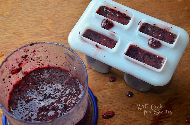 putting blueberry puree into popsicle molds 