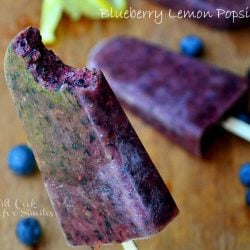 blueberry lemon popsicle with 1 bite held up and additional pop resting on table below