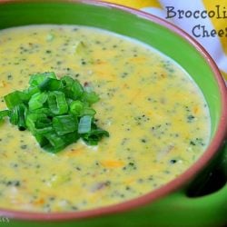 green clay bowl filled with broccoli bacon cheese soup with yellow and white chevron table cloth