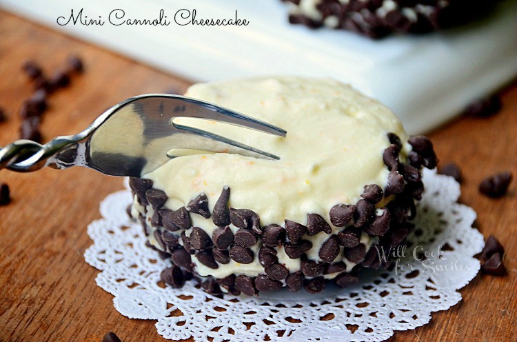 cannoli on a lace round paper with a fork cutting into it on a wood table 