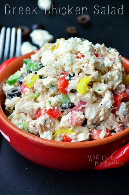 Greek chicken salad with peppers, tomatoes, and black olives in a orange bowl 