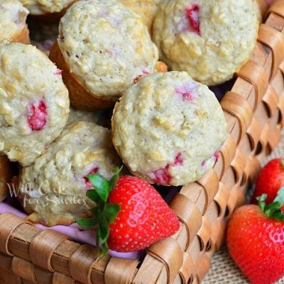 wicker basket filled with mini strawberry oat muffins with knife and butter spread on muffin on table