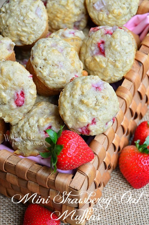 strawberry muffins in a basket with whole strawberries around it 