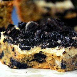 close up of oreo cheesecake bar on white plate with several more bars in background