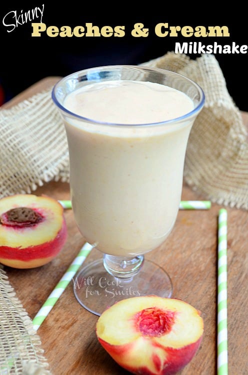 peaches and cream milk shake in a glass with sliced peaches on the table around it and green and white straws 