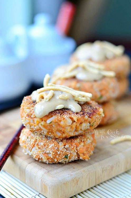 3 stacks of 2 salmon cakes each lined up on wooden cutting board with bamboo placemat below and chop sticks to left