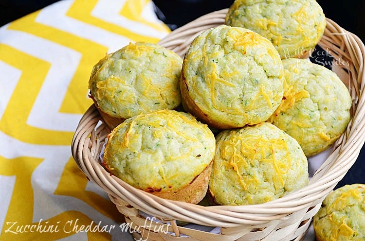 light brown wicker basket filled with zucchini cheddar muffins and 2 muffins below basket