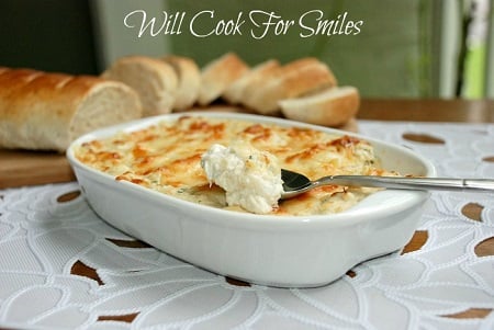 Crab Dip in a casserole dish with a spoon scooping some out 