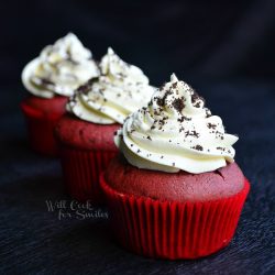 3 red velvet oreo topped cupcakes lined up on black table