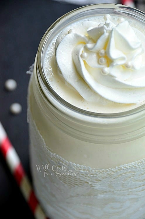 White Wedding Cake Milkshake in a mason jar with whipped cream on top and candy pearls 