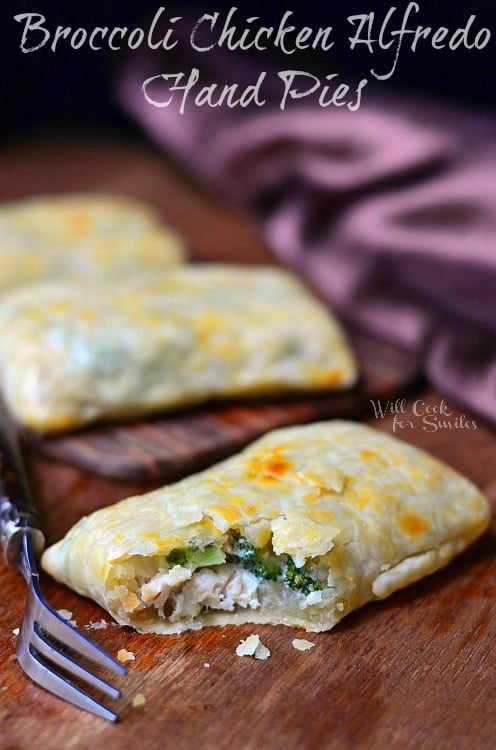 Broccoli Chicken Alfredo Hand Pies on cutting board with one cut open with chicken and broccoli showing 