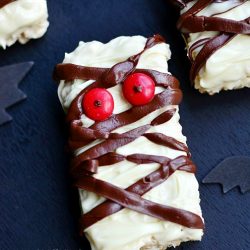 halloween decorated double chocolate rice krispie treats as mummies on black table