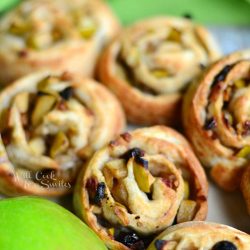 close up view of apple strudel rolls on live wood board with apple to bottom left