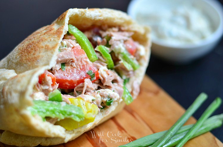 Greek Tuna Pita on a cutting board with tuna, tomatoes, and green peppers 