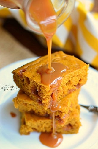 Pumpkin Caramel Blondies on a white plate with pumpkin syrup being poured over them 
