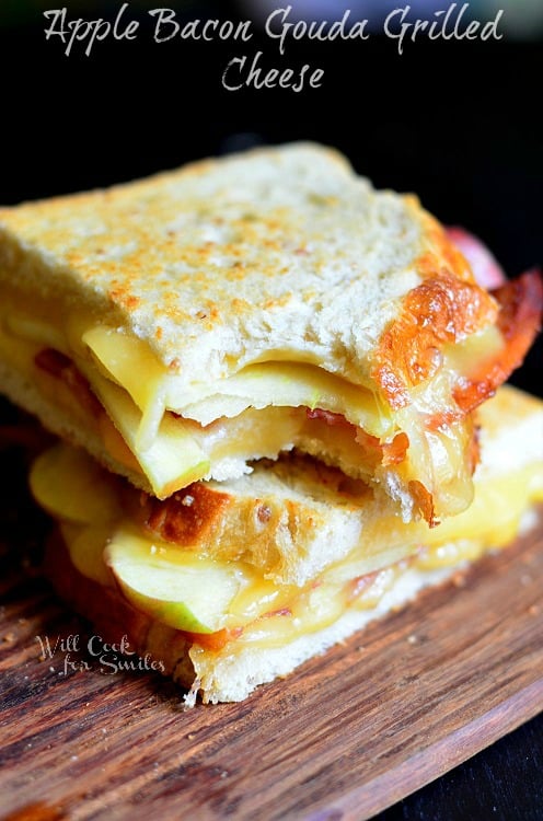 Apple Bacon Gouda Grilled Cheese with a bite out of it on the cutting board 